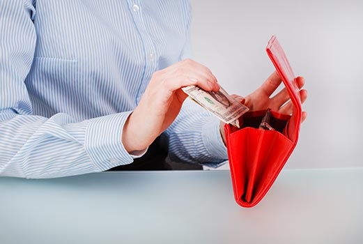 Kobieta wyciąga pieniądze z czerwonego portfela