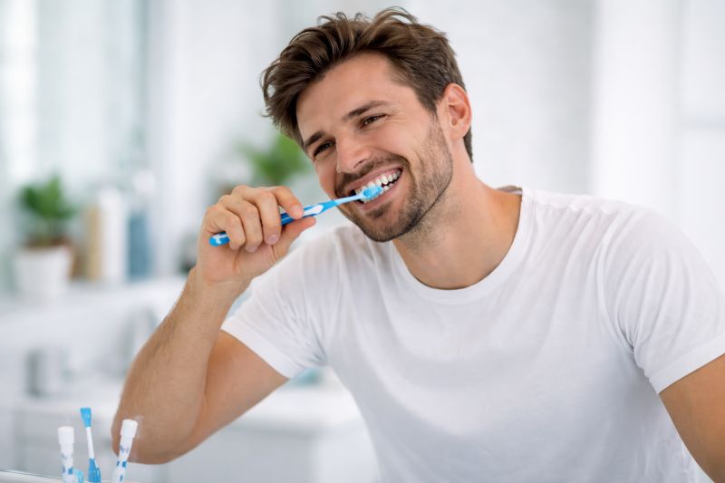 Mężczyzna szczotkujący zęby w łazience przed lustrem