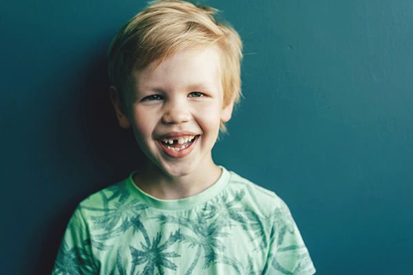 uśmiechnięte dziecko, które pokazuje, że nie ma jednego zęba.