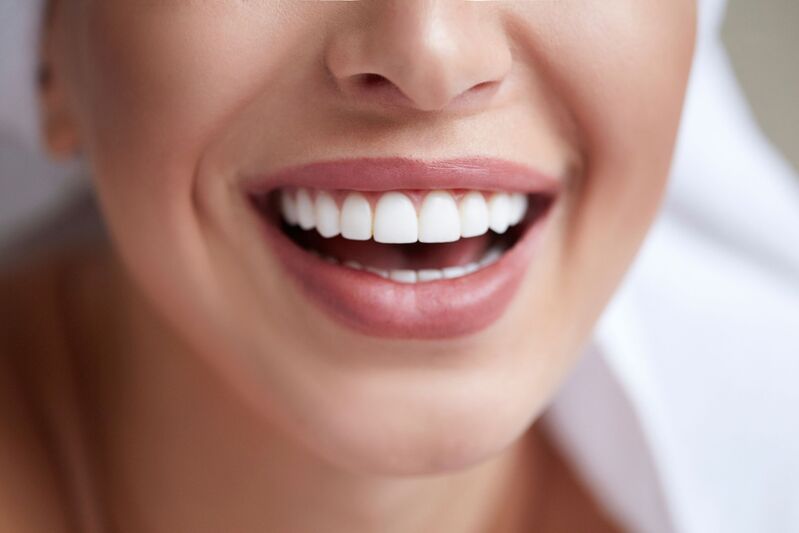Kobieta uśmiecha się i pokazuje zdrowe i białe zęby