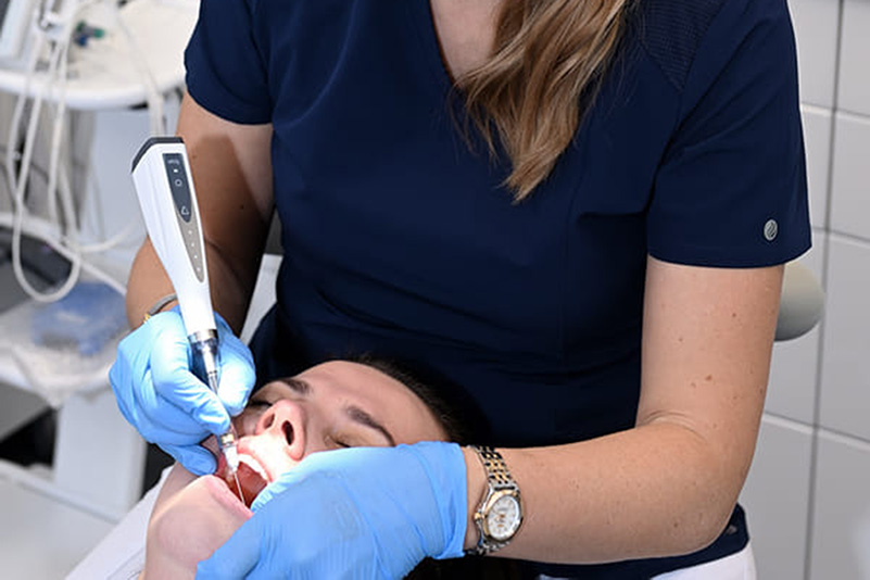 Dentystka podaje znieczulenie za pomocą urządzenia, pacjentowi na fotelu