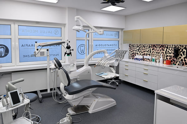 Gabinet dentystyczny Beauty Dentica. Na środku fotel dentystyczny, z lewej narzędzia, z prawej środki czyszczące