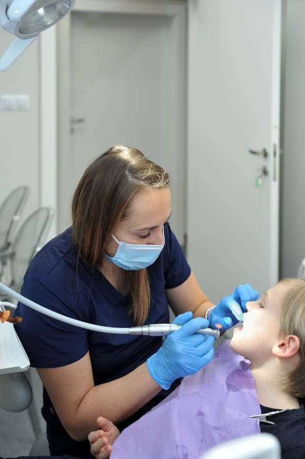 Lekarz Dentystka Joanna wykonuje czyszczenie zębów u pacjenta