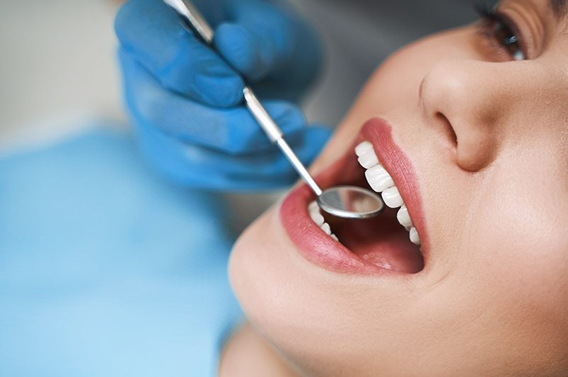 Dentysta sprawdza stan uzębienia u pacjentki Lekarz sprawdzający stan górnych zębów za pomocą lusterka dentystycznego